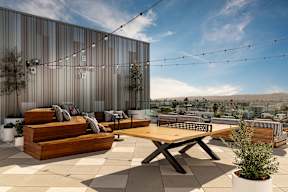 A modern outdoor seating area with wooden furniture and string lights.