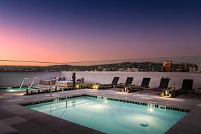 A swimming pool with lounge chairs and a sunset view.