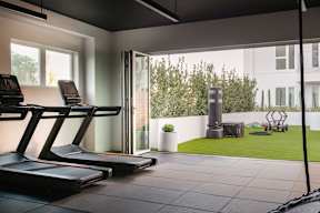 A treadmill is in a room with a view of a backyard.