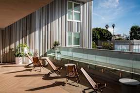 A patio with wooden chairs and a glass railing.