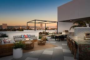 A modern outdoor living space with a view of the city skyline at dusk.