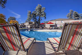 Two striped chairs are facing a pool.