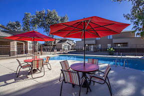 A red umbrella is in the foreground of a pool area.