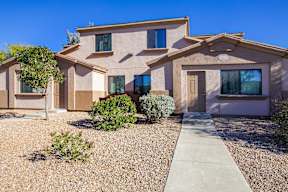 A house with a brown and beige exterior and a gravel driveway.