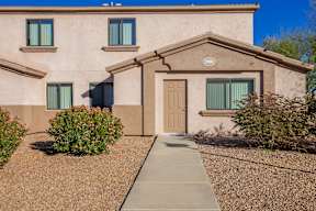 A beige house with a brown door and windows.