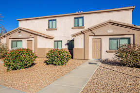 A beige house with a brown roof and a brown walkway in front.