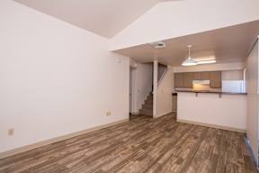 A room with wooden flooring and a staircase leading to another room.