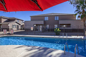 A swimming pool is surrounded by a fence and a building.