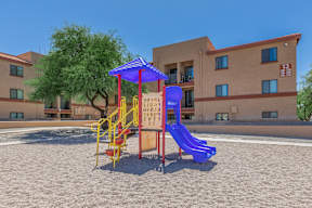 A playground with a blue slide and a yellow and red play structure.
