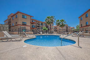 A pool surrounded by chairs and apartment buildings.