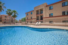 A swimming pool in front of a building with palm trees.