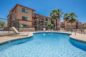 A swimming pool in front of a building with palm trees.