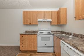 A kitchen with a white stove and wooden cabinets.