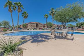 A pool surrounded by palm trees and chairs.