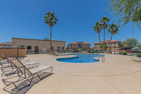 A pool surrounded by lounge chairs and palm trees.