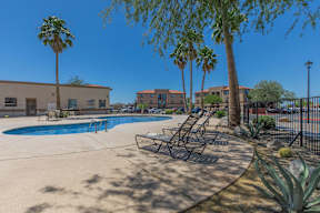 A pool surrounded by palm trees and lounge chairs.
