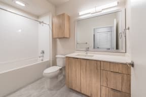 Blonde design package bathroom with ceramic tile floors, blonde wood cabinets, and quartz counters