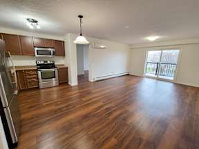 an empty kitchen and living room with wood flooring in an empty house