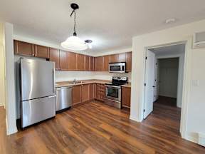 an empty kitchen with stainless steel appliances and wood flooring