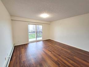 an empty living room with hard wood flooring and a window