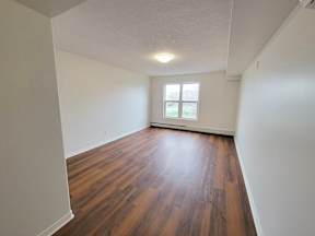 an empty living room with wood flooring and a window