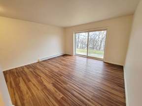 an empty living room with wood floors and a window