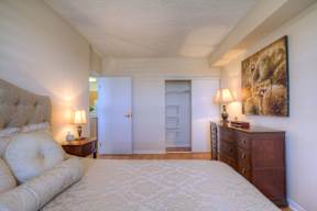 A bedroom with a large bed, a dresser, and a painting on the wall.