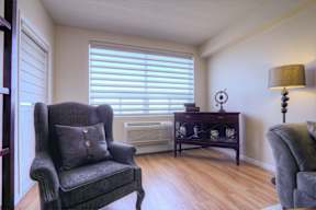 A chair with a pillow sits in a room with a wooden floor.