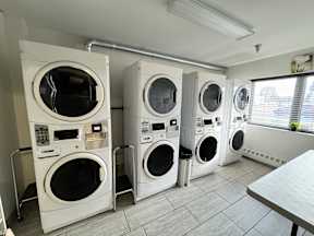 A row of white front load washing machines in a laundromat.