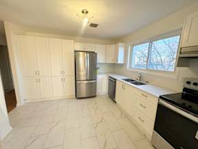A kitchen with white cabinets and a stainless steel refrigerator.