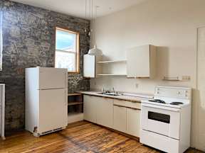 A kitchen with white appliances and wooden floors.