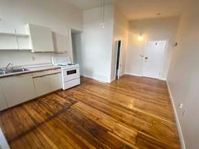 A kitchen with wooden floors and white cabinets.