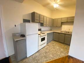 A kitchen with white appliances and wooden floors.