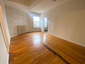 A room with wooden floors and a white brick wall.