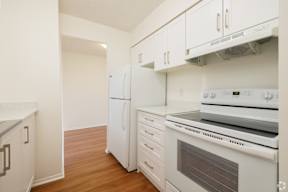 A white kitchen with a stove, oven, and refrigerator.