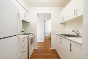A white kitchen with wood floors and white appliances.