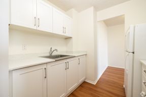 A kitchen with white cabinets and a white fridge.