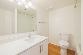 A white bathroom with a toilet, sink, and mirror.