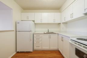 A white refrigerator and oven in a kitchen with wooden floors.