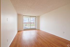 Empty room with wooden floor and sliding glass door.