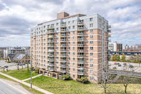 A large apartment building with a parking lot in front.