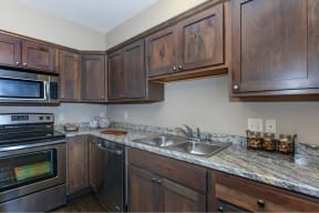 a kitchen with dark wood cabinets and granite countertops at InterUrban Apartments, Billings, MT 59106