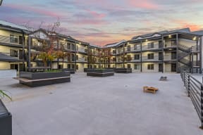 an empty courtyard with apartment buildings with a colorful sky above it