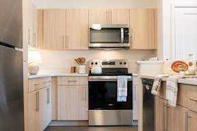 A modern kitchen with wooden cabinets and stainless steel appliances.at Copestone Apartments, Garden City, ID