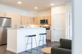 A kitchen with a white counter and bar stools.at Copestone Apartments, Idaho, 59808