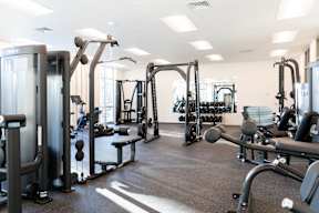 A gym with a variety of equipment including a squat rack, a leg press machine, and a bench press.at Copestone Apartments, Garden City, ID 59808