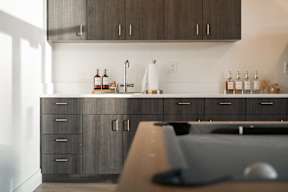 A kitchen with dark wood cabinets and a white backsplash.at Copestone Apartments, Garden City