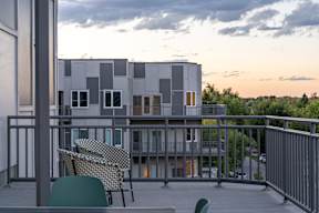 A modern building with a balcony and chairs.at Copestone Apartments, Garden City, ID 59808