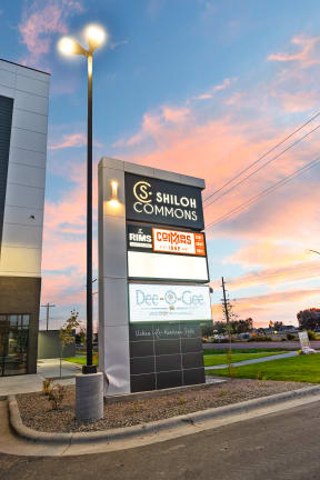 a sign in front of a building with a sunset in the background at Shiloh Commons, Billings, MT 59102
