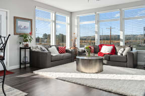 a living room with a large group of windows and a large couch with a round coffee table at Shiloh Commons, Billings, MT